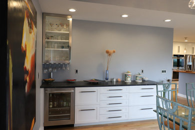 Mid-sized transitional u-shaped medium tone wood floor and brown floor eat-in kitchen photo in Other with shaker cabinets, white cabinets, granite countertops, blue backsplash, stainless steel appliances, black countertops, an undermount sink, stone tile backsplash and a peninsula