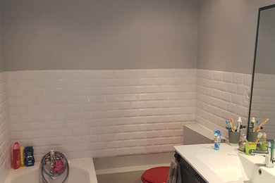 Aménagement d'une salle de bain contemporaine de taille moyenne pour enfant avec des portes de placard grises, une baignoire posée, WC séparés, un carrelage blanc, un carrelage métro, un mur gris, un sol en linoléum, un plan vasque, un sol gris et un plan de toilette blanc.