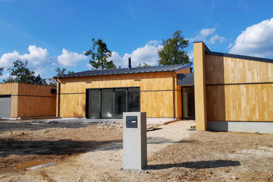 Cette image montre une façade de maison minimaliste en bois et bardage à clin de taille moyenne et à un étage avec un toit en appentis, un toit en métal et un toit gris.