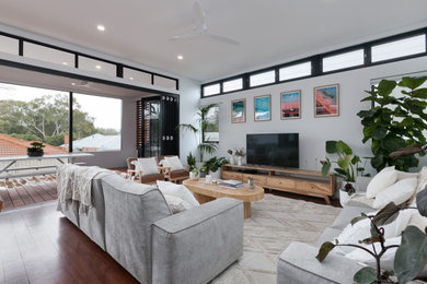 Modelo de sala de estar abierta tradicional grande con paredes blancas, suelo de madera oscura y televisor independiente