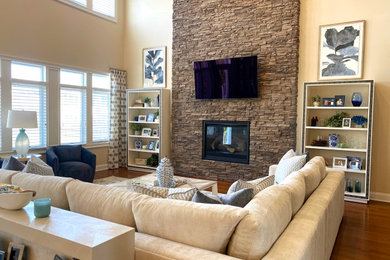 Example of a huge trendy formal and open concept medium tone wood floor and brown floor living room design in New York with beige walls, a standard fireplace, a stone fireplace and a wall-mounted tv