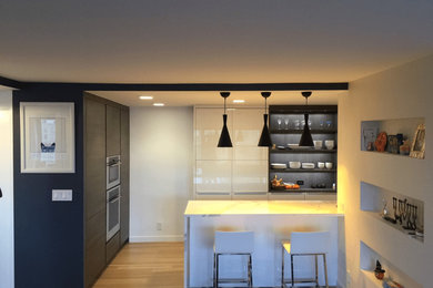 Example of a transitional galley medium tone wood floor and beige floor eat-in kitchen design in New York with an undermount sink, flat-panel cabinets, gray cabinets, quartz countertops, gray backsplash, stainless steel appliances and a peninsula