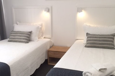 Ejemplo de habitación de invitados blanca costera pequeña con paredes blancas, moqueta y suelo gris