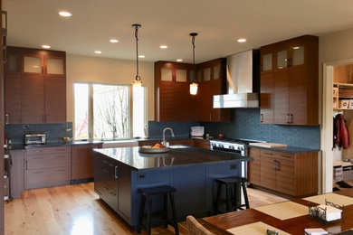 Example of a large u-shaped bamboo floor and brown floor eat-in kitchen design in Other with a farmhouse sink, flat-panel cabinets, medium tone wood cabinets, quartzite countertops, blue backsplash, glass tile backsplash, stainless steel appliances, an island and gray countertops
