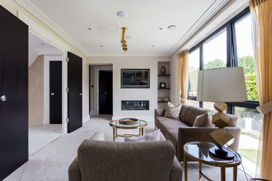 Photo of a mid-sized transitional enclosed living room in Hertfordshire with beige walls, carpet, a ribbon fireplace, a wall-mounted tv and grey floor.