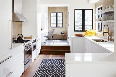 Transitional galley medium tone wood floor kitchen photo in Toronto with a double-bowl sink, flat-panel cabinets, white cabinets, beige backsplash and a peninsula