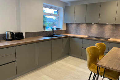Medium sized contemporary kitchen in Buckinghamshire with flat-panel cabinets, laminate countertops, a breakfast bar and brown worktops.