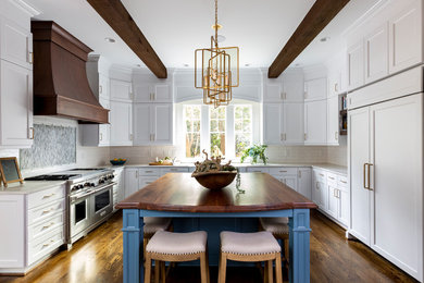 Inspiration for a large transitional u-shaped medium tone wood floor and brown floor eat-in kitchen remodel in Charlotte with a farmhouse sink, shaker cabinets, white cabinets, quartzite countertops, white backsplash, ceramic backsplash, paneled appliances, an island and white countertops