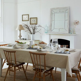 This is an example of a large scandinavian dining room in London with white walls, light hardwood floors, a standard fireplace and a plaster fireplace surround.