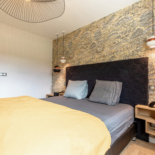 Inspiration pour une chambre design de taille moyenne avec un mur jaune, un sol en bois clair, aucune cheminée et un sol marron.