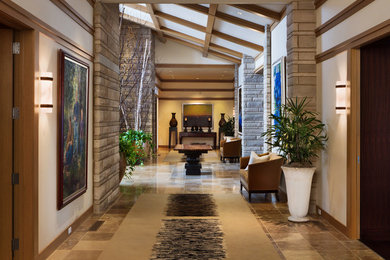 Inspiration for an expansive transitional hallway in Omaha with white walls, travertine floors and brown floor.