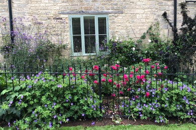 Photo of a small farmhouse front partial sun garden in Gloucestershire with a flowerbed, mulch and a metal fence.