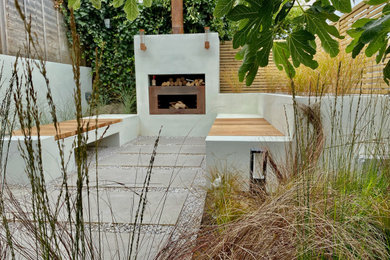 Small contemporary back partial sun garden for winter in Sussex with a fire feature, decorative stones and a wood fence.