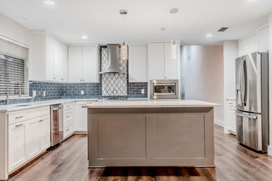 Open concept kitchen - mid-sized brown floor open concept kitchen idea in Dallas with a drop-in sink, shaker cabinets, white cabinets, quartzite countertops, blue backsplash, glass tile backsplash, an island and white countertops