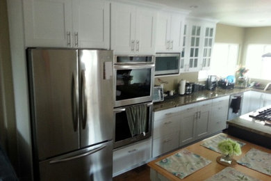 Example of a large minimalist l-shaped dark wood floor eat-in kitchen design in San Diego with shaker cabinets, white cabinets, stainless steel appliances, an island and a single-bowl sink