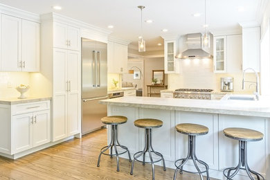 Kitchen pantry - transitional u-shaped light wood floor and brown floor kitchen pantry idea in San Francisco with an undermount sink, shaker cabinets, white cabinets, marble countertops, white backsplash, ceramic backsplash, stainless steel appliances, a peninsula and beige countertops