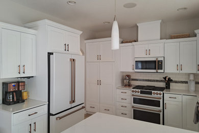 Mid-sized u-shaped kitchen pantry photo in Edmonton with white cabinets, white backsplash and an island