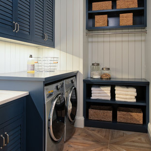 Medium sized classic l-shaped separated utility room in Minneapolis with louvered cabinets, blue cabinets, composite countertops, white walls, light hardwood flooring, a side by side washer and dryer and beige floors.