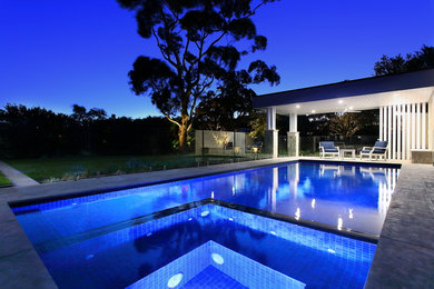 Design ideas for a mid-sized contemporary backyard rectangular pool in Sydney with a pool house and natural stone pavers.