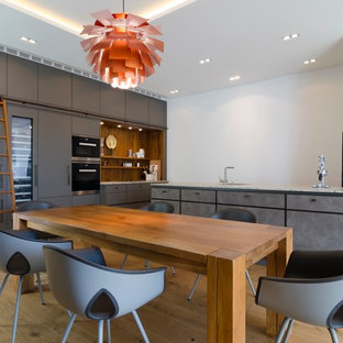 Offene, Große Moderne Küche in L-Form mit flächenbündigen Schrankfronten, grauen Schränken, hellem Holzboden und Halbinsel in Hamburg