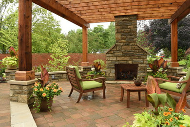 This is an example of a large transitional backyard patio in Columbus with brick pavers and a pergola.