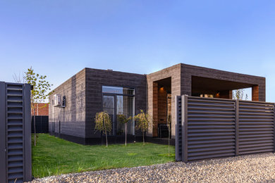 На фото: одноэтажный, коричневый частный загородный дом в современном стиле с комбинированной облицовкой и плоской крышей с