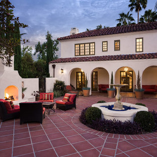 ロサンゼルスの大きい地中海スタイルのおしゃれな中庭のテラス (タイル敷き、日よけなし、屋外暖炉) の写真