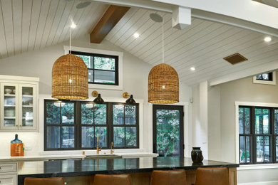 Example of a large transitional u-shaped light wood floor, gray floor and vaulted ceiling open concept kitchen design in San Francisco with a farmhouse sink, beaded inset cabinets, white cabinets, quartzite countertops, white backsplash, ceramic backsplash, paneled appliances, an island and white countertops
