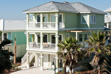 Example of a large beach style green three-story stucco exterior home design in Orlando