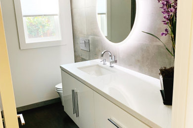 Example of a mid-sized minimalist 3/4 painted wood floor and black floor bathroom design in San Francisco with flat-panel cabinets, white cabinets, white walls, an undermount sink, quartz countertops and white countertops