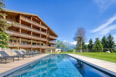 Cette image montre un grand piscine avec aménagement paysager chalet rectangle avec une terrasse en bois.