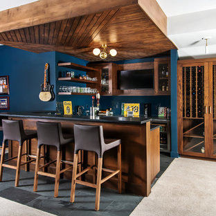 デンバーのミッドセンチュリースタイルのおしゃれな着席型バー (ガラス扉のキャビネット、濃色木目調キャビネット、青いキッチンパネル、グレーの床、黒いキッチンカウンター) の写真