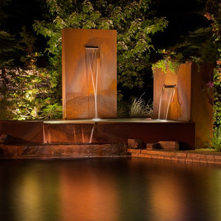 Mid-sized modern backyard patio in Detroit with a water feature and natural stone pavers.