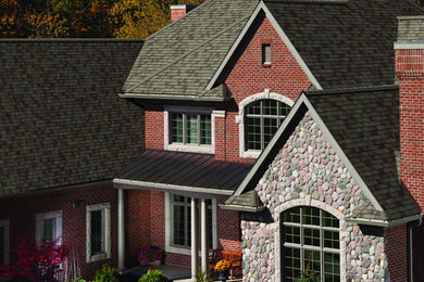 This is an example of a large arts and crafts two-storey brick red exterior in New York with a clipped gable roof.