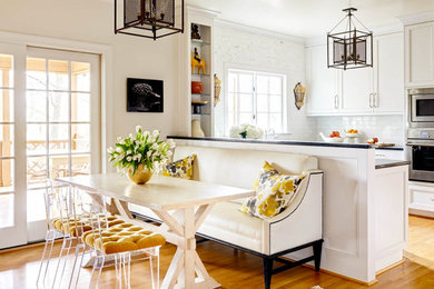 Large trendy u-shaped light wood floor enclosed kitchen photo in Charlotte with a farmhouse sink, recessed-panel cabinets, white cabinets, white backsplash, subway tile backsplash, stainless steel appliances and an island