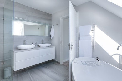 Exemple d'une grande salle de bain principale chic avec un placard à porte plane, des portes de placard blanches, une baignoire posée, une douche à l'italienne, WC séparés, un carrelage gris, des carreaux de céramique, un mur gris, un sol en carrelage de céramique, un lavabo posé, un plan de toilette en granite, un sol gris, aucune cabine et un plan de toilette gris.