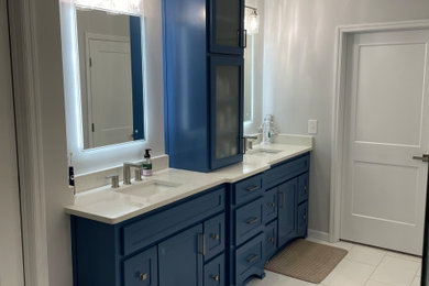 Example of a large gray tile ceramic tile, white floor and double-sink bathroom design in Atlanta with shaker cabinets, blue cabinets, a two-piece toilet, gray walls, an undermount sink, solid surface countertops, a hinged shower door, white countertops and a built-in vanity