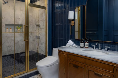 Example of a trendy 3/4 blue tile and ceramic tile marble floor, gray floor, single-sink and wall paneling wet room design in New York with beaded inset cabinets, brown cabinets, a bidet, blue walls, an undermount sink, marble countertops, a hinged shower door, blue countertops, a niche and a freestanding vanity
