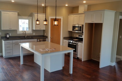 Example of a mid-sized arts and crafts l-shaped medium tone wood floor and brown floor eat-in kitchen design in Other with a double-bowl sink, shaker cabinets, white cabinets, quartz countertops and an island