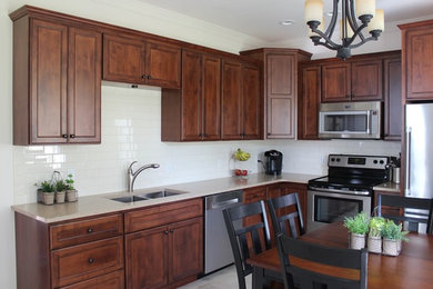 Eat-in kitchen - mid-sized traditional l-shaped ceramic tile and gray floor eat-in kitchen idea in Other with a double-bowl sink, recessed-panel cabinets, dark wood cabinets, quartzite countertops, white backsplash, subway tile backsplash and stainless steel appliances