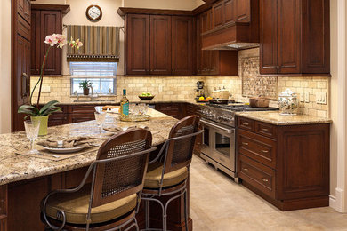 Photo of a mid-sized traditional l-shaped eat-in kitchen in Houston with an undermount sink, raised-panel cabinets, dark wood cabinets, granite benchtops, beige splashback, cement tile splashback, stainless steel appliances, porcelain floors, with island and beige floor.