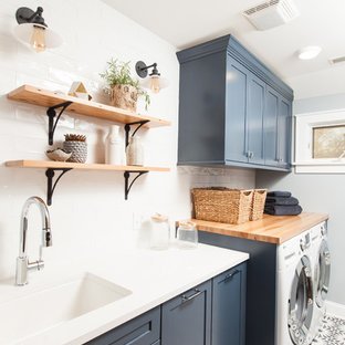 Inredning av en modern mellanstor vita linjär vitt tvättstuga enbart för tvätt, med en undermonterad diskho, skåp i shakerstil, blå skåp, bänkskiva i kvarts, blå väggar, betonggolv, en tvättmaskin och torktumlare bredvid varandra och blått golv