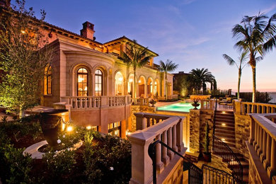 Inspiration for a large mediterranean beige two-story stone house exterior remodel in Orange County with a hip roof and a tile roof