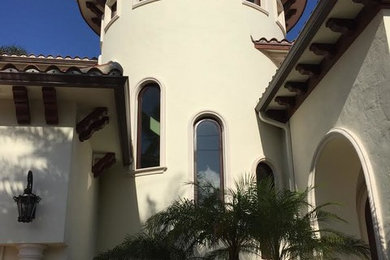 Large traditional beige two-story stucco house exterior idea in Miami with a hip roof and a tile roof