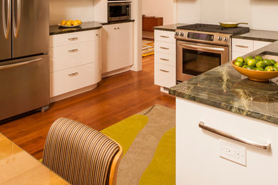 Eat-in kitchen - mid-sized contemporary u-shaped medium tone wood floor eat-in kitchen idea in DC Metro with flat-panel cabinets, white cabinets, granite countertops, white backsplash, glass sheet backsplash, stainless steel appliances and an undermount sink