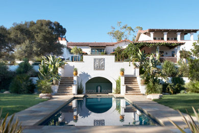 This is an example of a large mediterranean two-storey stucco white house exterior in Santa Barbara with a hip roof and a tile roof.