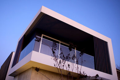 Idées déco pour une façade de maison beige moderne en béton à un étage.