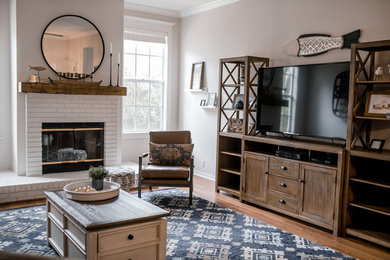 Large country open concept laminate floor and brown floor family room photo in Tampa with gray walls, a standard fireplace, a brick fireplace and a tv stand