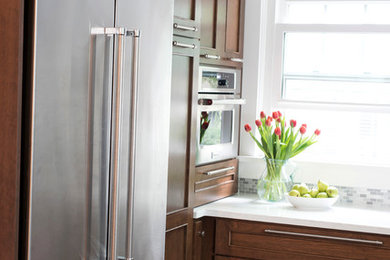 Mid-sized transitional u-shaped vinyl floor and multicolored floor kitchen photo in Other with an undermount sink, shaker cabinets, brown cabinets, quartz countertops, gray backsplash, marble backsplash, stainless steel appliances, no island and white countertops