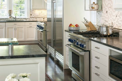 Design ideas for a traditional l-shaped kitchen in Boston with soapstone benchtops, stainless steel appliances, white cabinets and grey splashback.